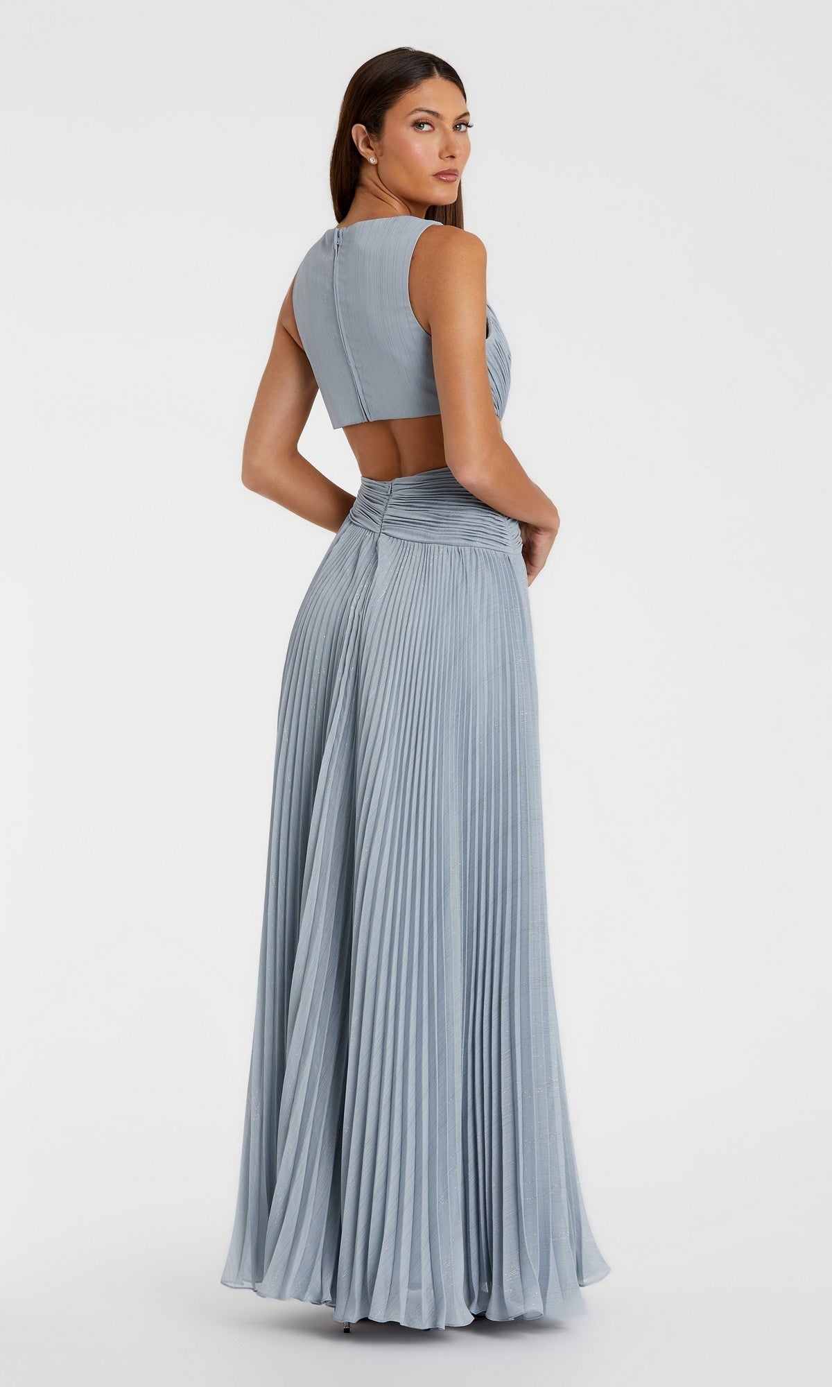 A woman in the Lilac Long Pleated Formal Dress (Mac Duggal 49938) with a v-neck and cut-out back stands facing away, looking over her shoulder against a plain white background.